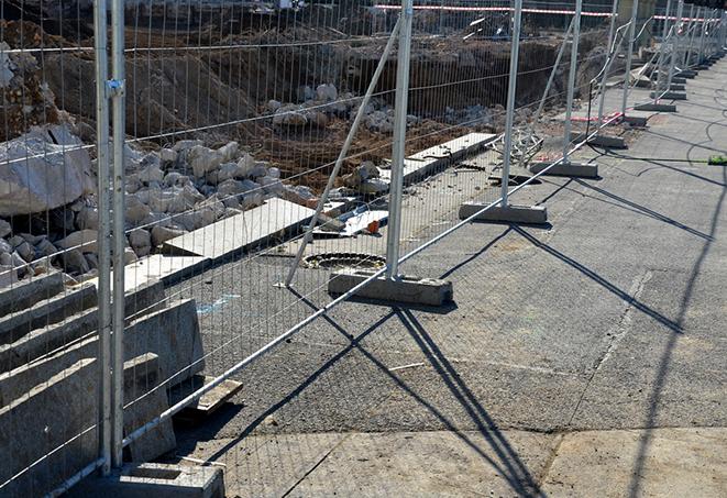 a construction worker assembling temporary fence panels for a construction site